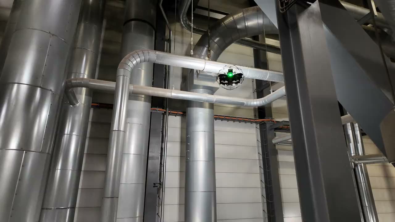 Inspektionsdrohne im Schutzkäfig zwischen großen Rohrleitungen und Rohrbögen