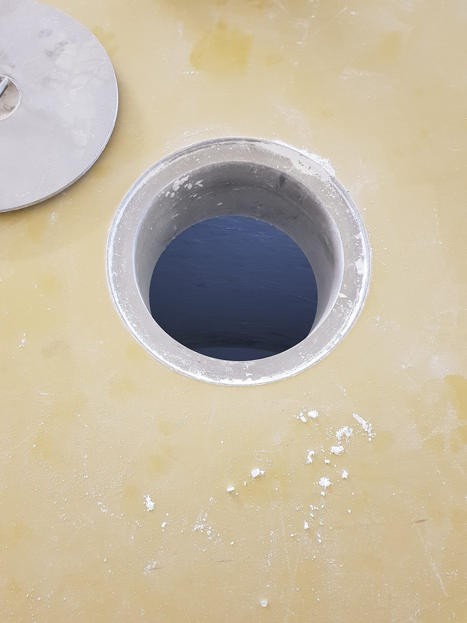Blick von oben in eine runde Einstiegsöffnung in der Silodecke, daneben der Deckel