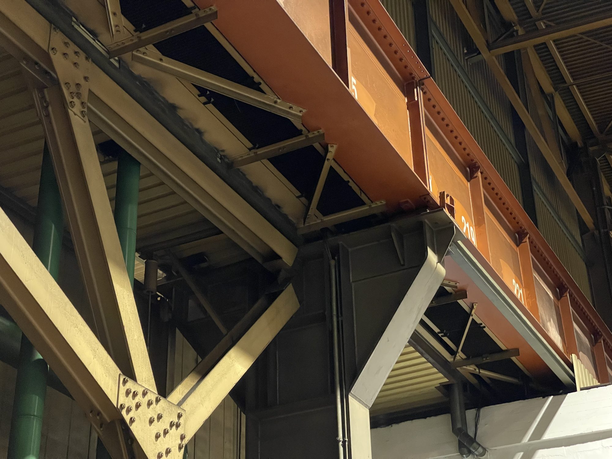 Genietetes Stahlfachwerk einer Halle mit Knotenblechen, daneben ein genieteter Kranbahnträger auf einer Stützenkonsole