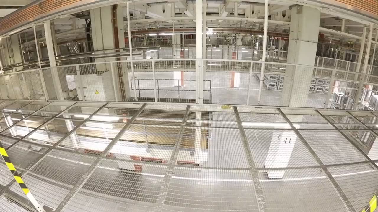 Drohnenflug über einer Stahlbühne mit Gitterrostboden in einer Produktionshalle