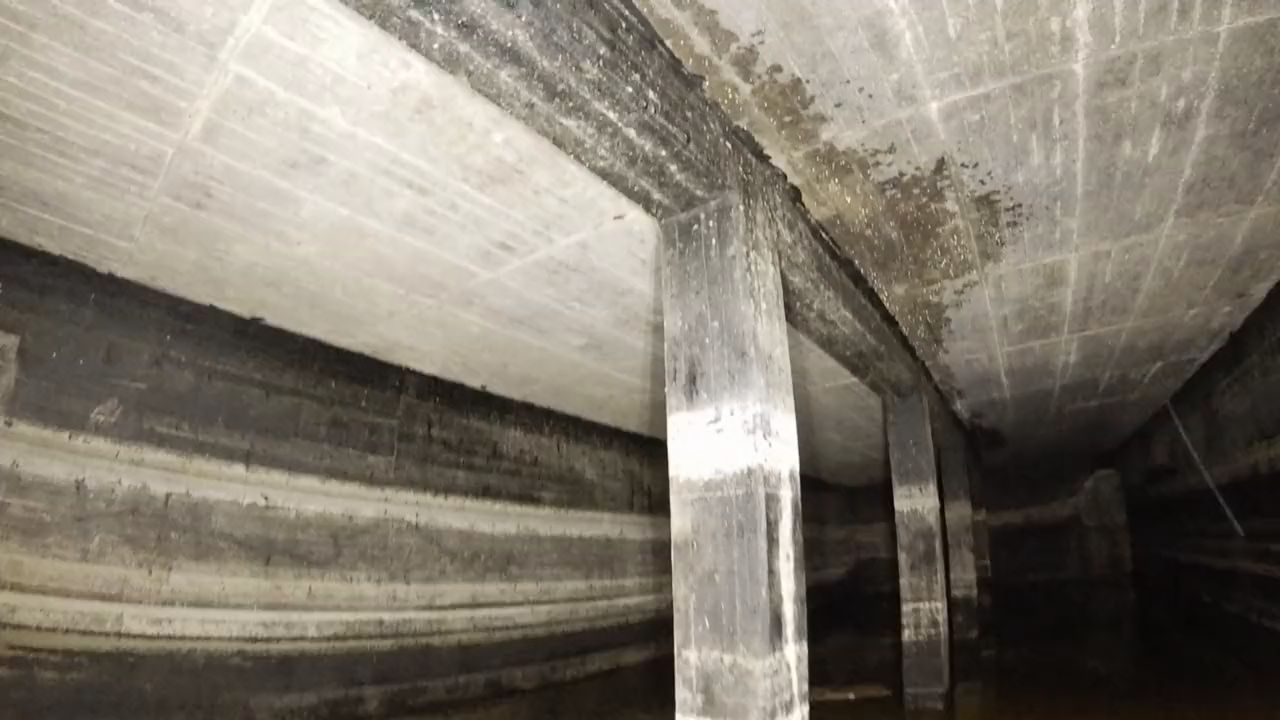 Blick nach oben auf Betondecke, Unterzug und eine Stütze in einem unterirdischen Becken