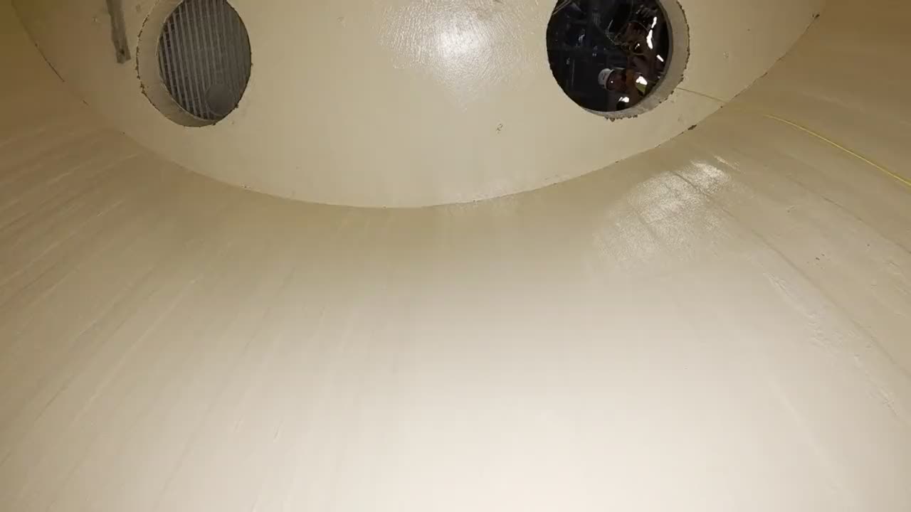 Blick aus dem Inneren des Silos nach oben zur Silodecke mit zwei Öffnungen, durch eine schaut ein Teammitglied herein